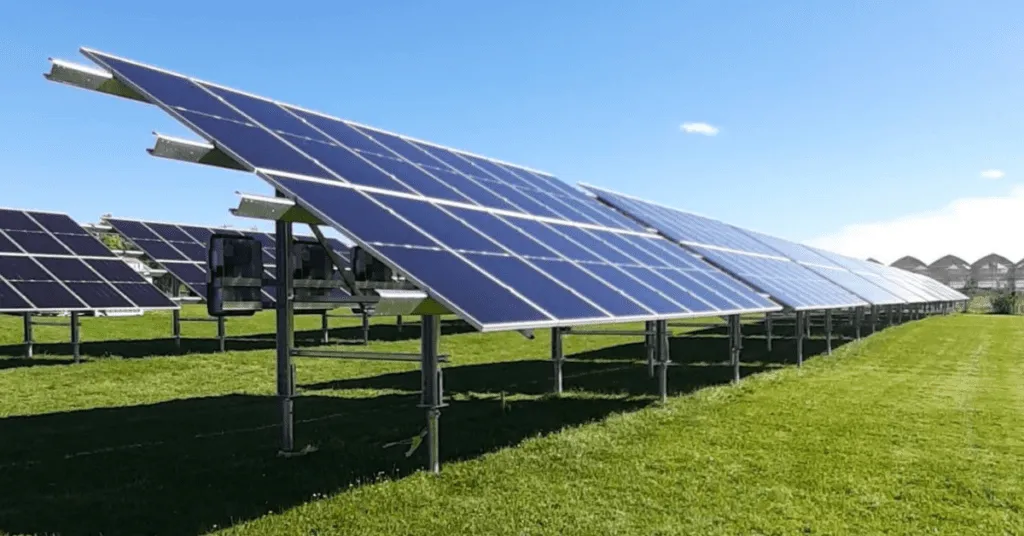 Rows of solar panels installed on screw piles in a green field.