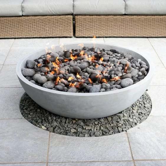 Modern outdoor fire pit with lava rocks, set on a stone platform, perfect for patio or deck decor.