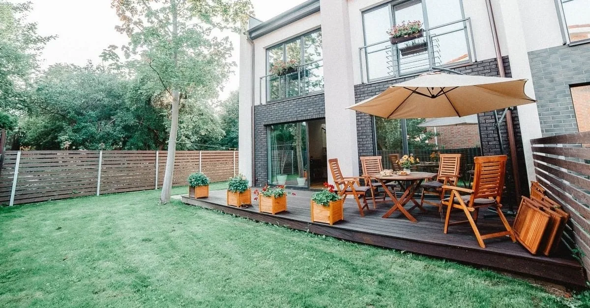 Modern backyard with a wooden deck, outdoor seating, and a stylish fence surrounding the green lawn.