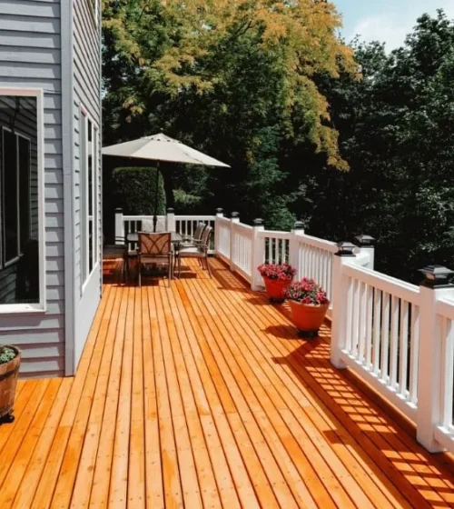 Wooden deck with white railings, outdoor seating, and potted plants.