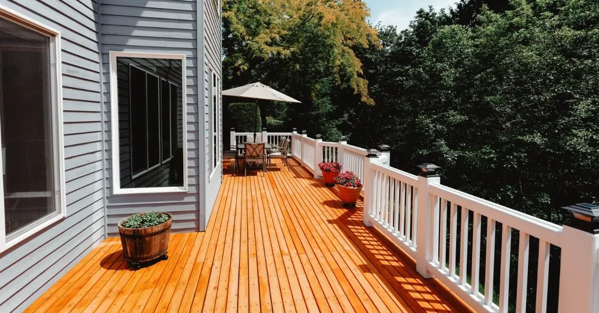 Wooden deck with white railings, outdoor seating, and potted plants.