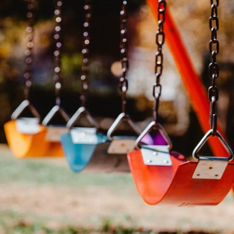 Colorful swings hanging in a park, depicting a welcoming and joyful play area for children.