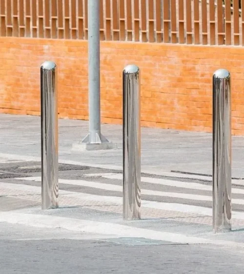 Stainless steel bollards securely installed on a street sidewalk, illustrating how screw piles provide stability and security in public spaces.