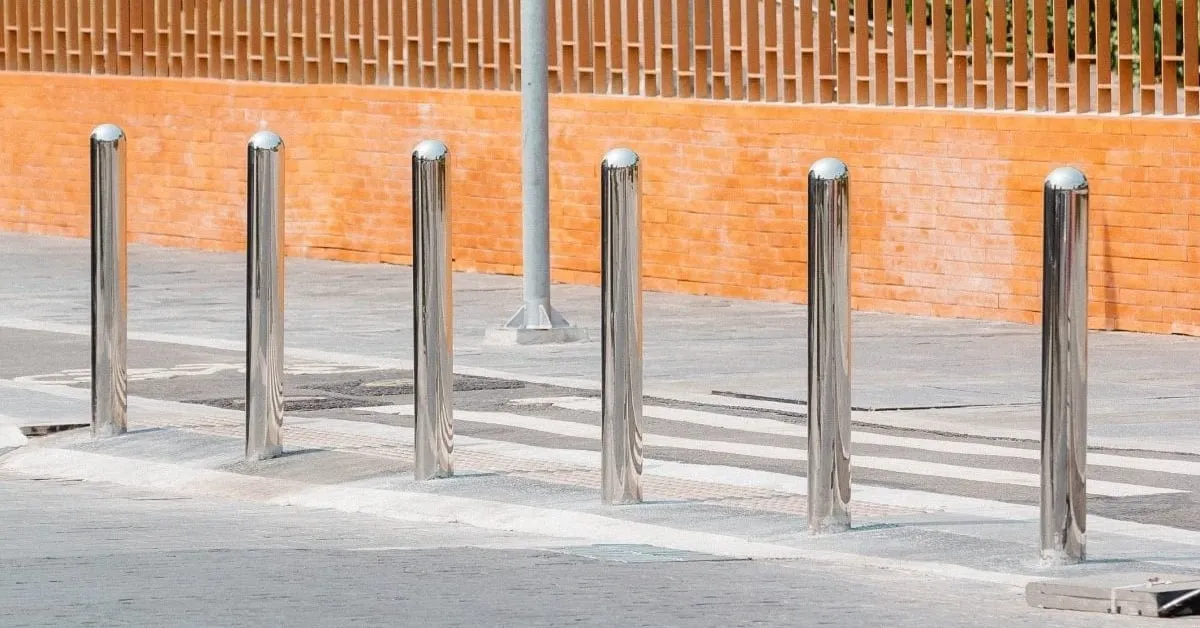 Stainless steel bollards securely installed on a street sidewalk, illustrating how screw piles provide stability and security in public spaces.