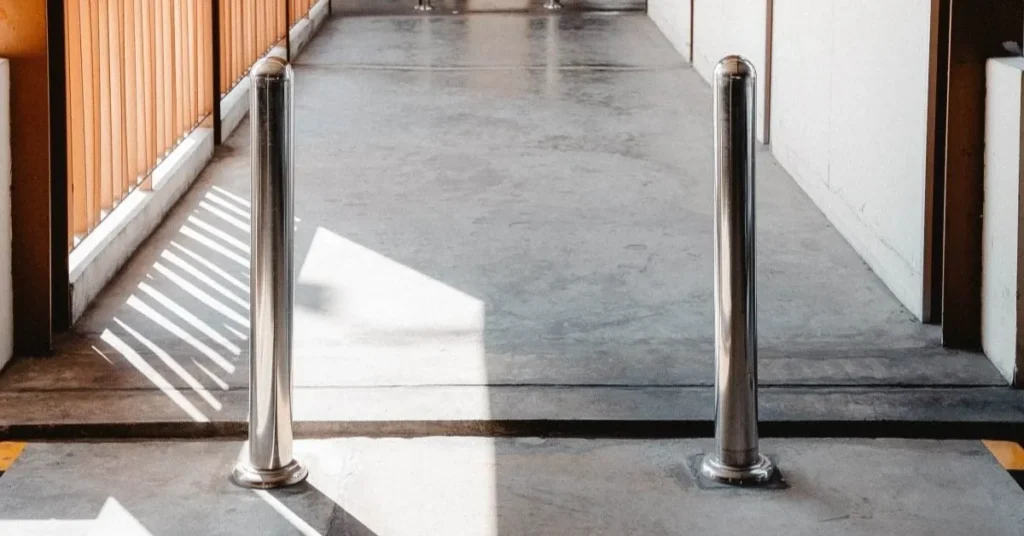 Two stainless steel bollards installed on a concrete pathway, showing the security and stability provided by screw piles.