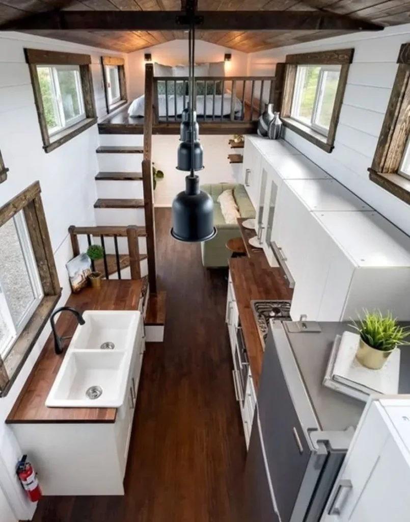 Modern tiny house kitchen with wood accents and loft bedroom