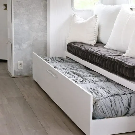 Compact living space featuring a sofa with a pull-out bed and built-in storage, optimizing space for a tiny house.