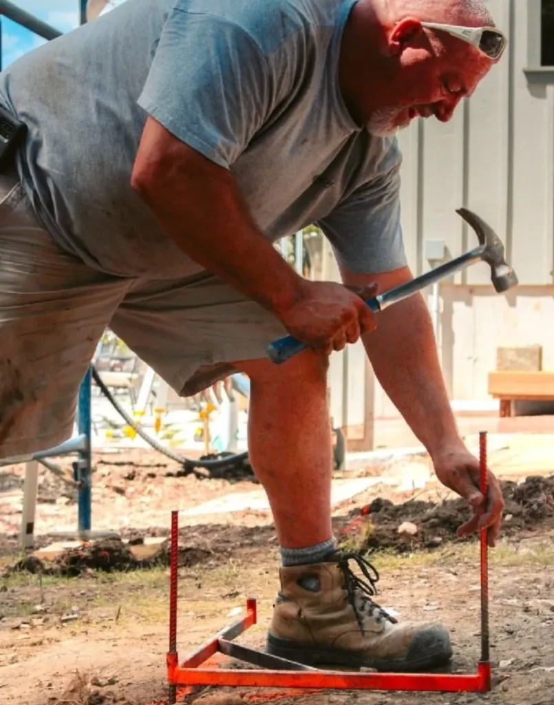 A construction worker hammering a stake into the ground, symbolizing the hard work and aspirations behind the growth of a small town like Wellington.