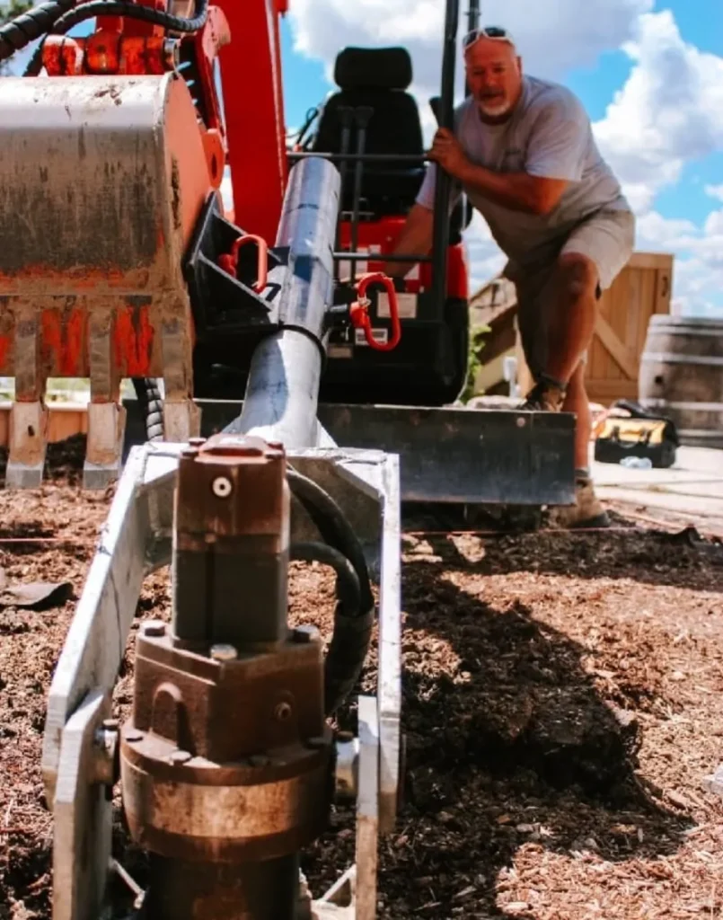 A construction worker operating heavy machinery to install screw piles, illustrating the ambitious development efforts in Wellington, a town with big dreams.