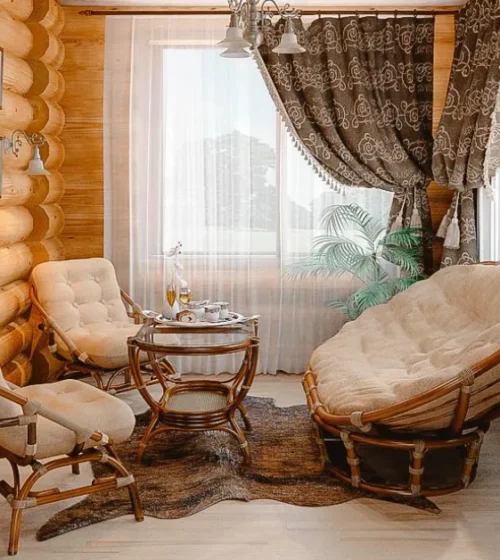 Cozy cabin-style sitting area with rustic wood walls, cushioned chairs, and natural light.