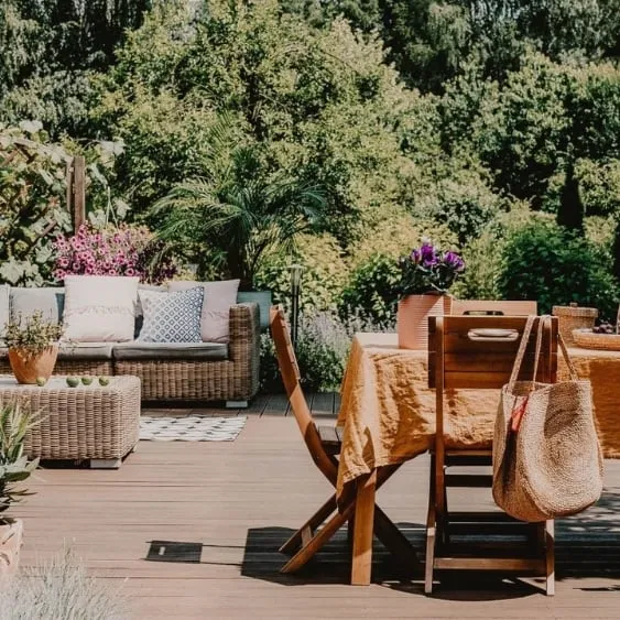 A beautifully arranged outdoor space featuring a dining table, comfortable seating, and vibrant greenery, perfect for family gatherings.