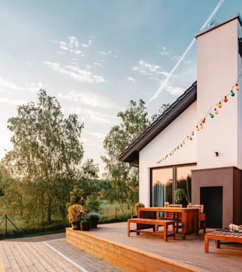 A beautifully designed deck area with wooden furniture and colorful string lights, creating a cozy outdoor space for relaxation and gatherings.