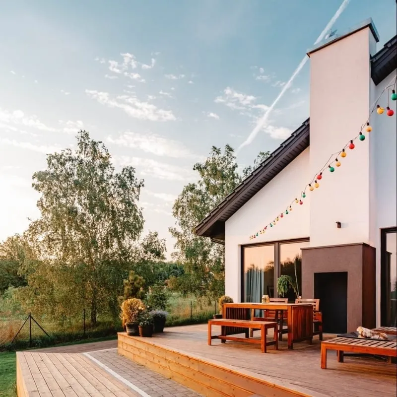 A beautifully designed deck area with wooden furniture and colorful string lights, creating a cozy outdoor space for relaxation and gatherings.