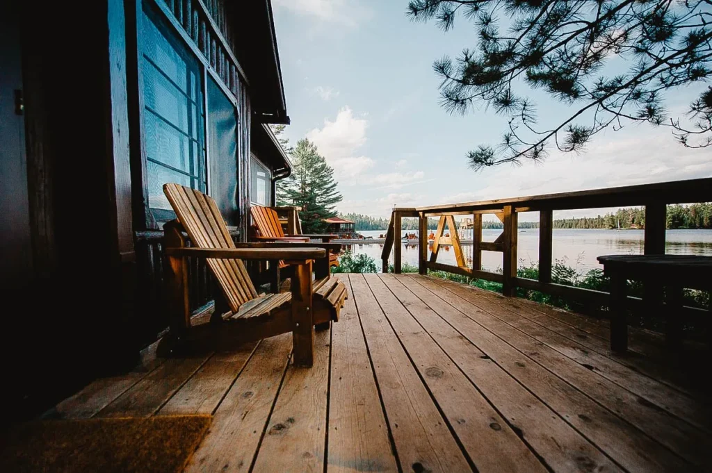 Wooden deck with Adirondack chairs overlooking a peaceful lake