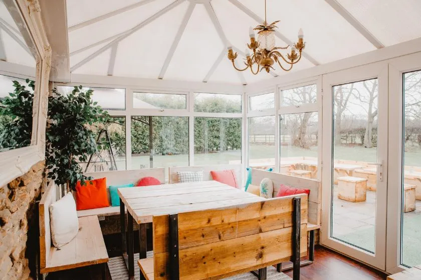 Cozy sunroom with wooden furniture and bright cushions.