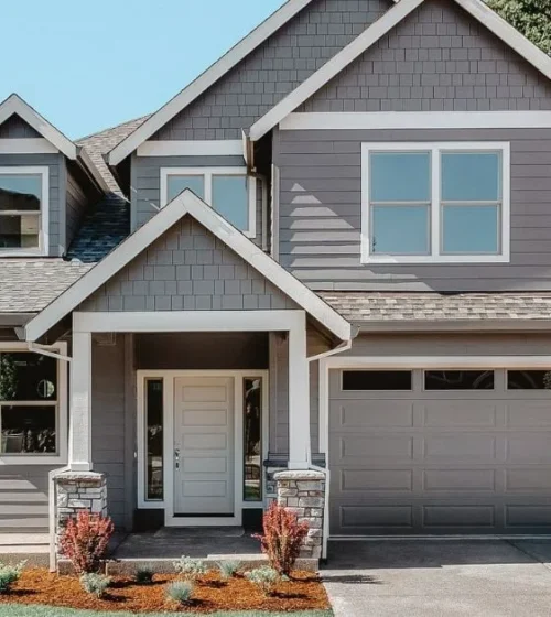 Modern two-story house with a well-maintained front yard and a large garage, showcasing a solid foundation and classic architectural style.