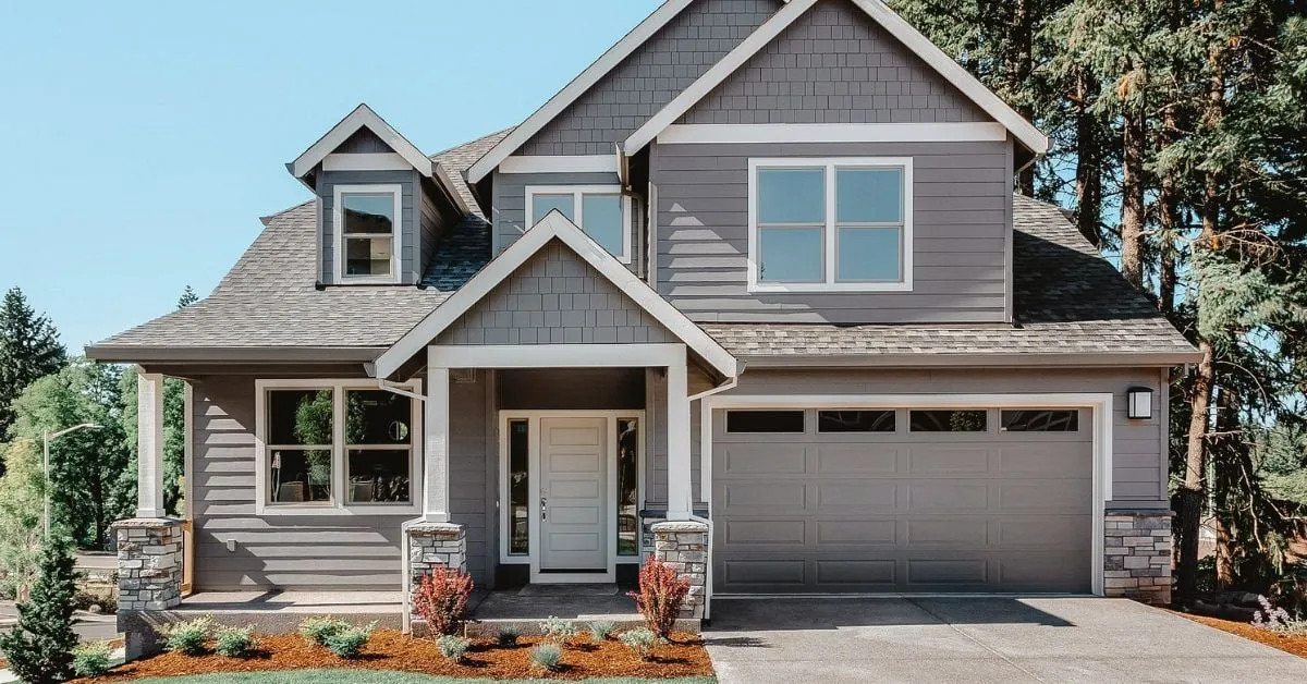 Modern two-story house with a well-maintained front yard and a large garage, showcasing a solid foundation and classic architectural style.