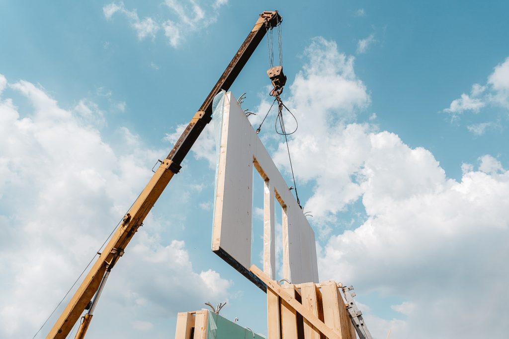 Process of crane construction of new and modern modular house from composite sip panels against background with beautiful blue sky