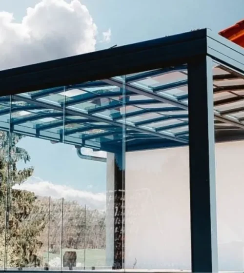 Modern sunroom with glass walls and sleek black frame structure.