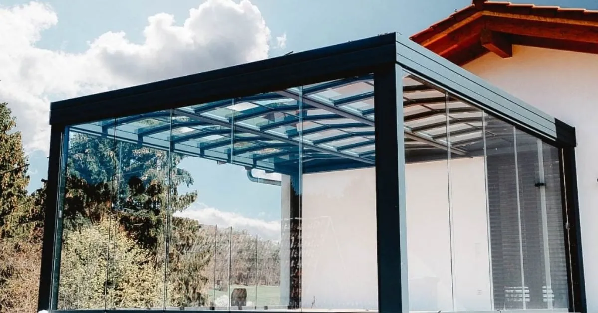 Modern sunroom with glass walls and sleek black frame structure.