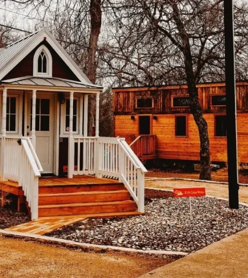 A charming tiny house with a welcoming porch, surrounded by trees, showcasing the concept of minimalist living.