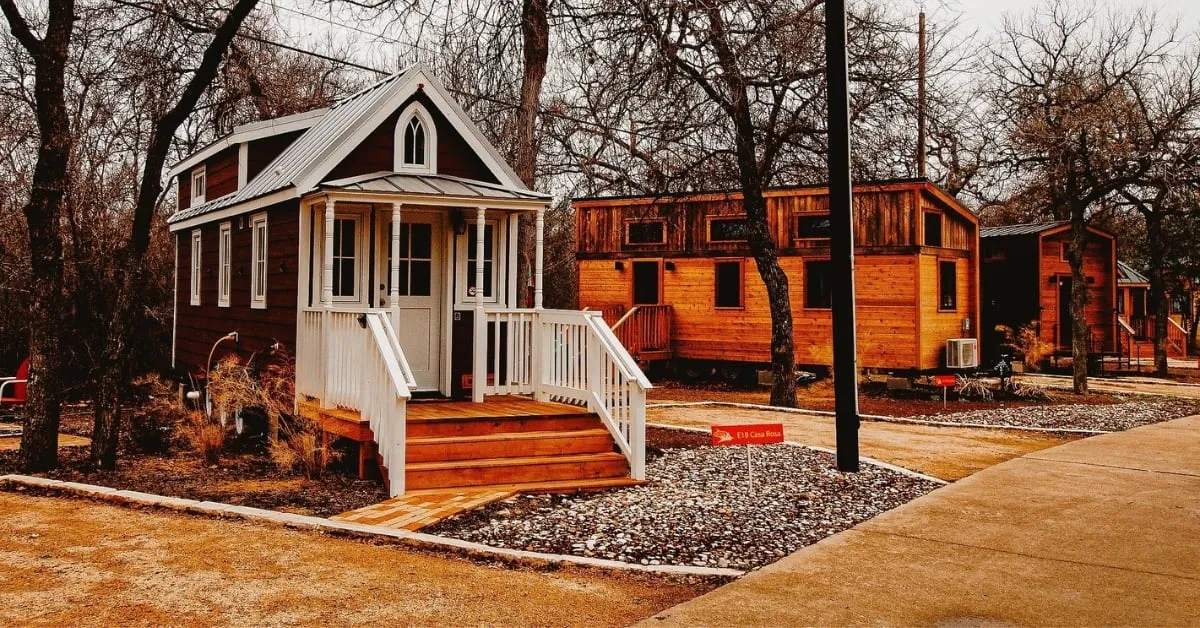 A charming tiny house with a welcoming porch, surrounded by trees, showcasing the concept of minimalist living.