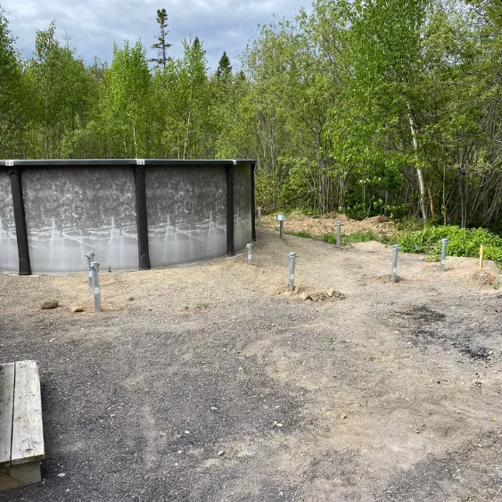 Pool area with screw piles installed in the ground, ready for a deck transformation.