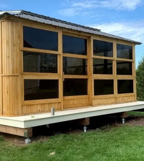 Wooden sunroom elevated on screw piles in a green landscape