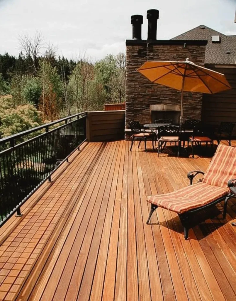 Grande terrasse en bois avec chaise longue, parasol et vue sur la forêt