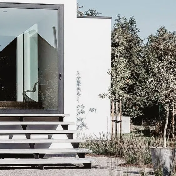 Modern outdoor stairs leading to a minimalist home entrance with a large glass door.