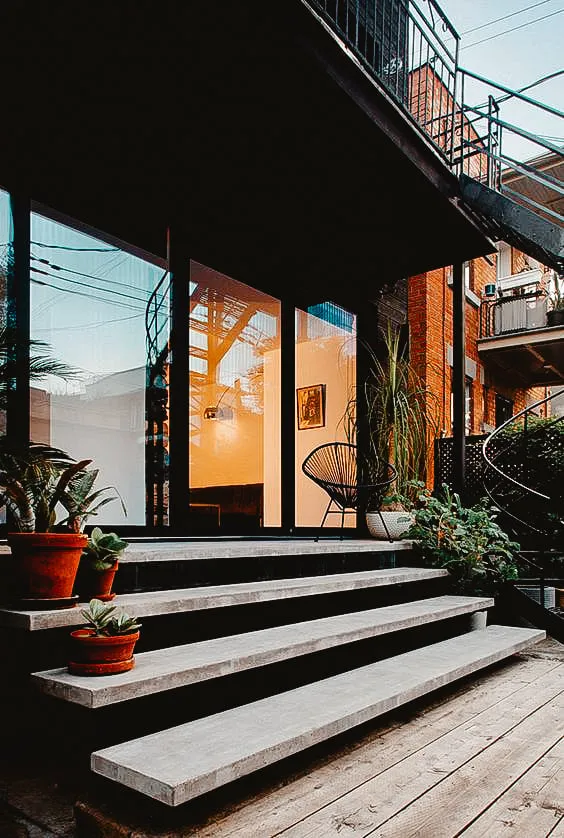 Modern outdoor concrete steps leading to a stylish balcony with potted plants.