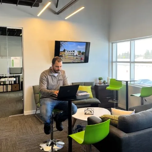 Postech Screw Piles employee working on a laptop in a modern, bright office lounge area.