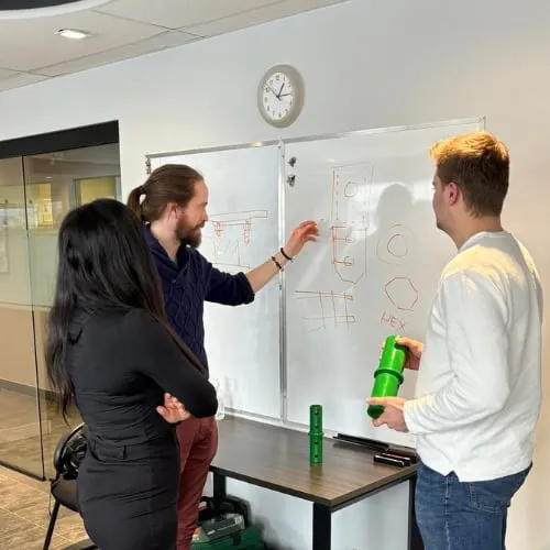 Postech Screw Piles team members collaborating on a project, discussing ideas in front of a whiteboard.