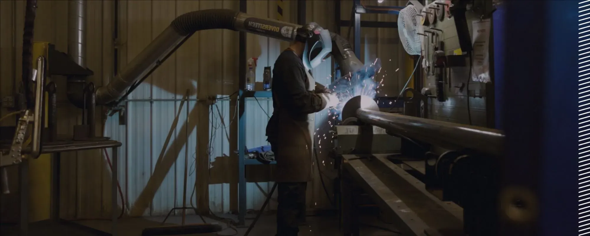 A worker wearing protective gear welding a steel pile in a factory, demonstrating precision and adherence to industry standards.